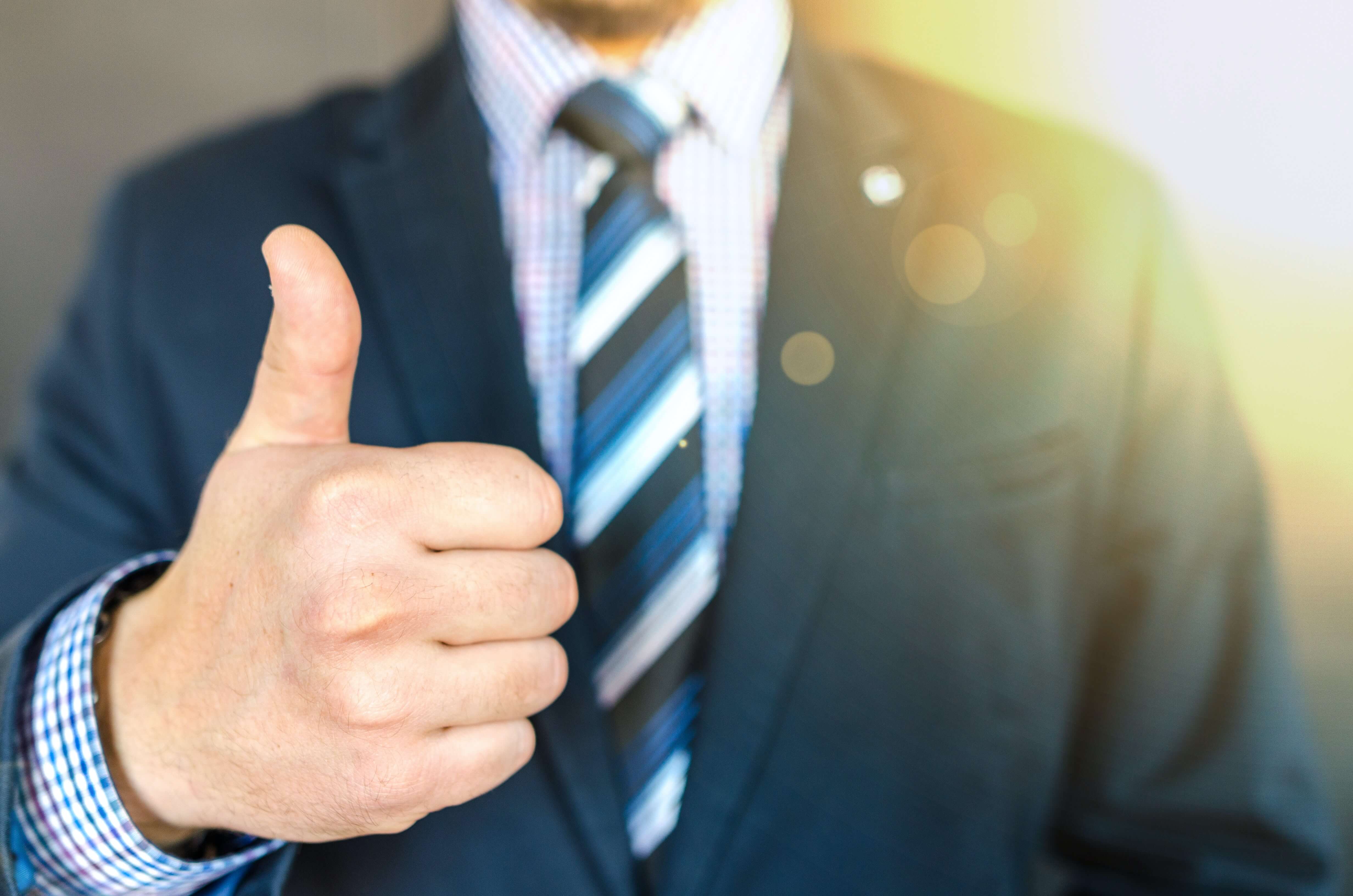  A man in a business suit giving a thumb up.